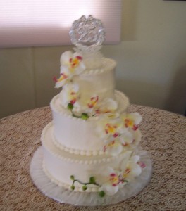 A three layer cake with white frosting and flowers.