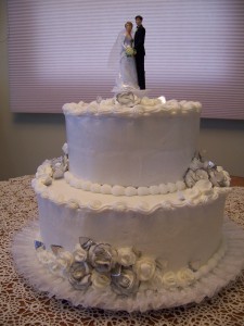 A wedding cake with two layers and a bride on top.