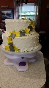 A two layer cake with white frosting and yellow leaves.