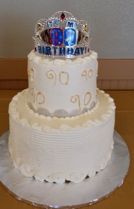 A white birthday cake with a crown on top.