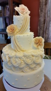 A white wedding cake with flowers on top of it.