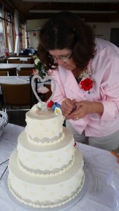 A woman is cutting the cake at her wedding.