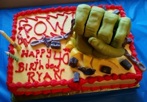 A birthday cake with hulk fist and pow lettering.